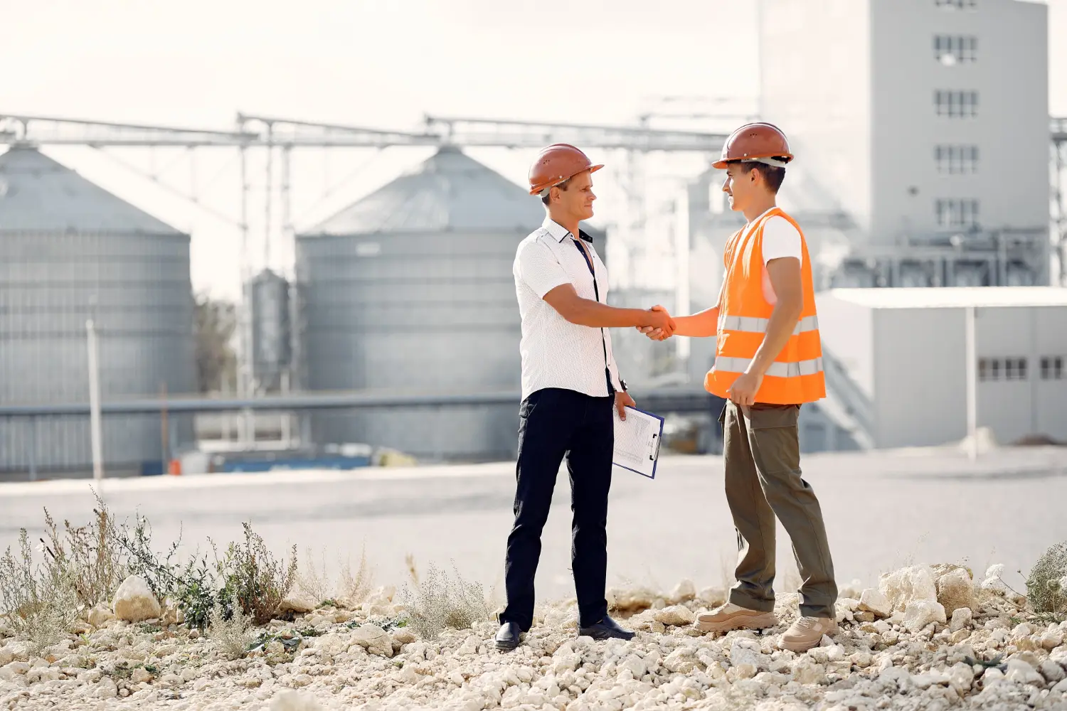 Two workers shaking hands at a site, representing leadership