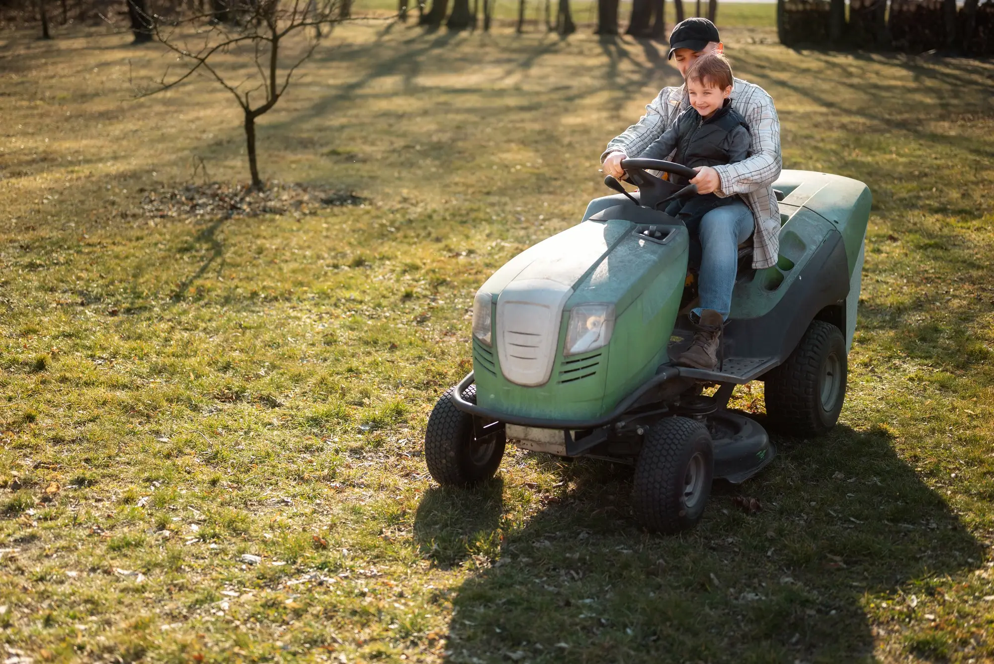 A father and son, mowing lawn on their lawn mower